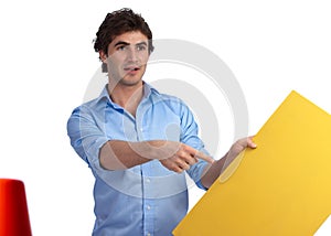 Young construction foreman with yellow sign