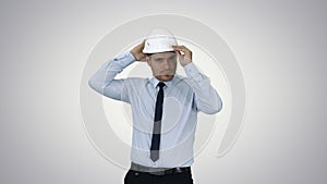 Young construction worker in hard hat on gray background on grad