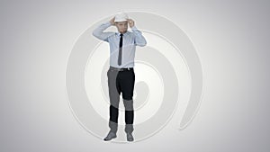 Young construction worker in hard hat on gray background on grad