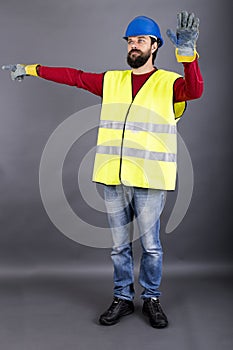 Young construction worker with hardhat directing traffic, showing stop sign