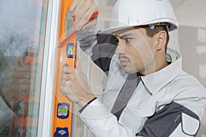 Young construction worker installing window in house