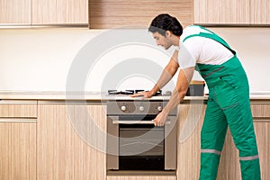 The young contractor repairing oven in kitchen