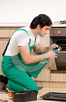 The young contractor repairing oven in kitchen