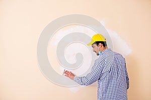 The young contractor sanding wall down with sandpaper