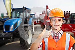 Young contractor shows blue agricultural tractor
