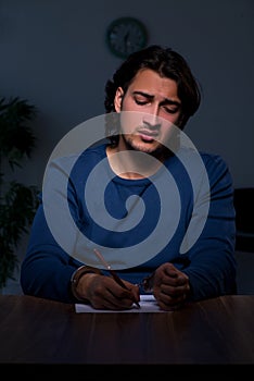 Young convict man sitting in dark room