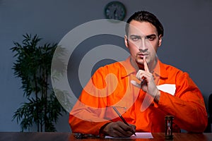 Young convict man sitting in dark room