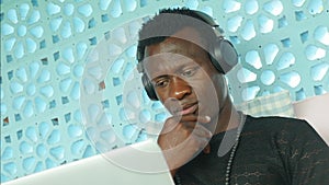 Young cool and attractive black African American hipster man with headphones networking relaxed with mobile phone and laptop