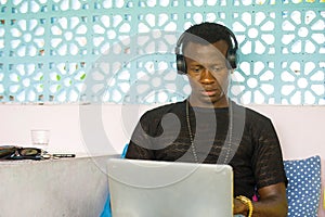 Young cool and hipster black afro American business man networking with laptop computer and headphones concentrated and thoughtful