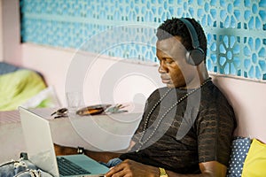 Young cool and hipster black afro American business man networking with laptop computer and headphones concentrated and thoughtful