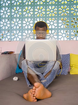 Young cool and hipster black afro American business man networking with laptop computer and headphones concentrated and thoughtful