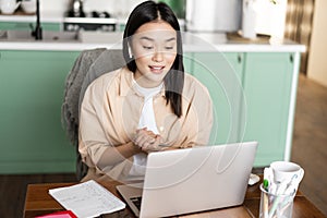Young corporate woman working from home. Asian girl has online classes remotely, talking on video chat, internet lecture