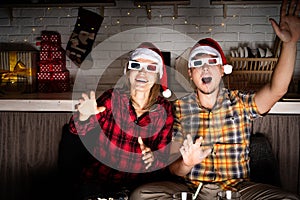 Young couple in 3D glasses watching movies at home at christmas