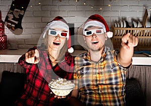 Young couple in 3D glasses watching movies at home at christmas