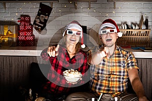 Young couple in 3D glasses watching movies at home at christmas