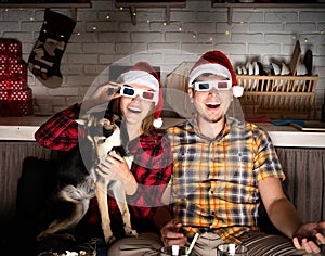 Young couple in 3D glasses watching movies at home at christmas