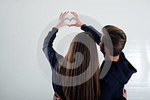 A young couple standing back looking at the white wall shows to the heart