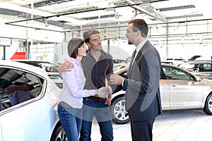 Young couple is advised by the seller at the car dealership