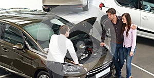 Young couple is advised by the seller at the car dealership