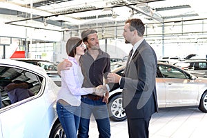 Young couple is advised by the seller at the car dealership photo