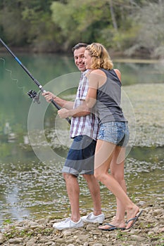 Young couple angling standing on river shore