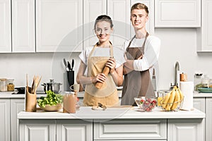 young couple in aprons looking at camera