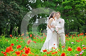 Young couple in the area of red poppies in the park.