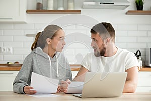 Young couple arguing about bills or document at home kitchen