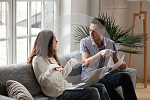 Young couple arguing about high bills with laptop and documents