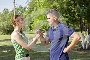 Young couple arguing while sitting on bench in park. Problems in relationship
