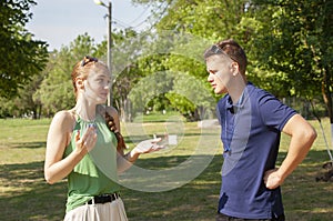 Young couple arguing while sitting on bench in park. Problems in relationship
