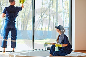 Young couple as professional cleaners in blue uniform cleaning bathroom