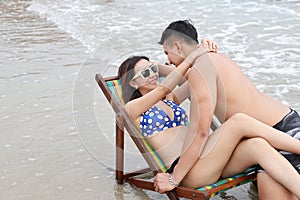 Young couple asian people are in love. they wearing blue bikini, sunglasses and black swimming suit. woman and man hugging and