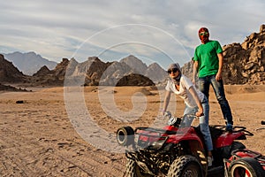 Young couple on ATV quad bike with traditional bedouin head scarfs in desert