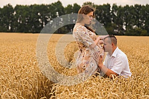 Young couple awaiting baby among the wheat field