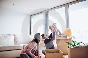 Young couple with a baby and cardboard boxes moving in a new home.