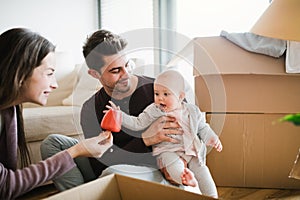Young couple with a baby and cardboard boxes moving in a new home.