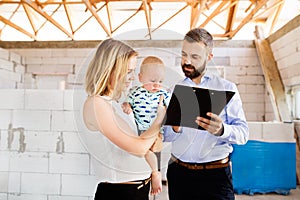 Young couple with a baby at the construction site.