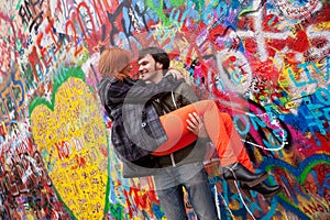 Young couple on the Background John Lennon Wall, Prague