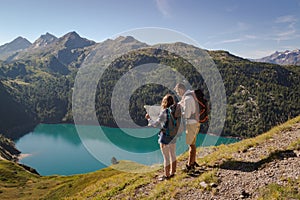 Young couple with backpack reading a map in the swiss alps. Lake ritom as background