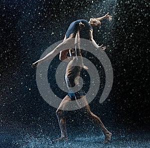 Young couple of ballet dancers dancing unde rwater drops