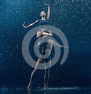 Young couple of ballet dancers dancing unde rwater drops