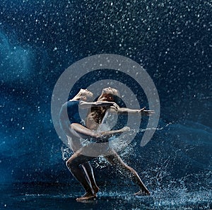 Young couple of ballet dancers dancing unde rwater drops