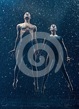 Young couple of ballet dancers dancing unde rwater drops