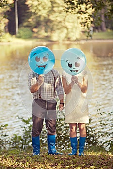 Young couple with balloons in their hands on the coast of the lake. Man and woman are in love. Concept for postcard