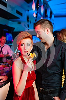 Young couple in bar or club drinking cocktails