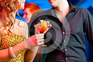 Young couple in bar or club drinking cocktails