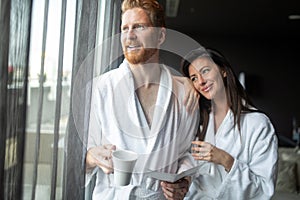 Young couple in bathrobes embracing and looking away in spa center