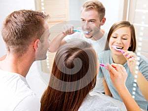 Young couple in the bathroom brushing teeth