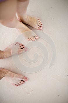 Young couple at the beach. Footprints at sand, foot of woman and man.